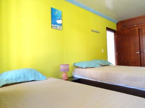 Una habitación con dos camas, una puerta de madera y un cuadro en la pared.