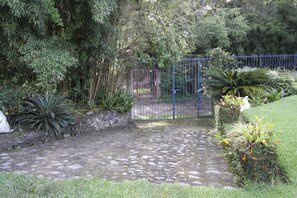 A stone pathway leading to a gated area surrounded by lush greenery and various plants. - El Refugio de las Palomas (Tepoztlán)