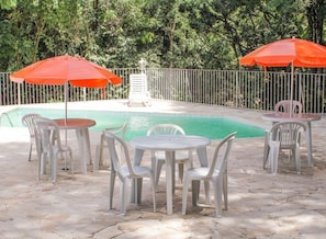 Una piscina al aire libre, sillones reclinables de piscina