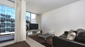 A modern living room with a large window, a flat-screen TV, a coffee table, and a sofa.