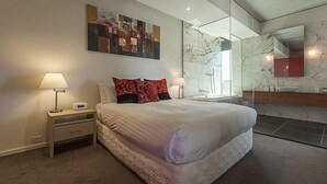 Un dormitorio moderno con una cama grande, una mesita de noche, un espejo en la pared y una pared con diseño de mármol.