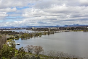 A large body of water with a bridge in the background, surrounded by trees and buildings.