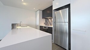 A modern kitchen with a large island, stainless steel appliances, and minimalist cabinetry. - Accommodate Canberra - The ApARTments (Canberra)