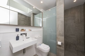 A modern bathroom with a white sink, mirror, and toilet.
