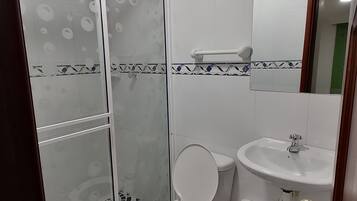 Une salle de bain avec des toilettes, un lavabo et une douche.