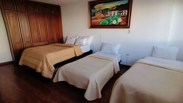 A hotel room with two beds, wooden wardrobe, and a painting on the wall.