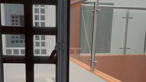 Blick durch ein Fenster mit Metallgitter, das ein Gebäude mit mehreren Fenstern und einer Glastür zeigt.