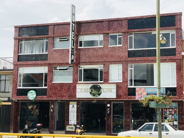 A hotel with a marbled facade, multiple windows, and a sign that reads "CALI FLOW".