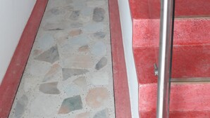 Eine Treppe mit roten Stufen und einem Metallgeländer, die zu einer Zwischenebene führt.