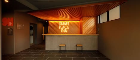 A reception area with a modern design, featuring a reception desk, two bar stools, and a sign that reads "SMART PLACE INN".
