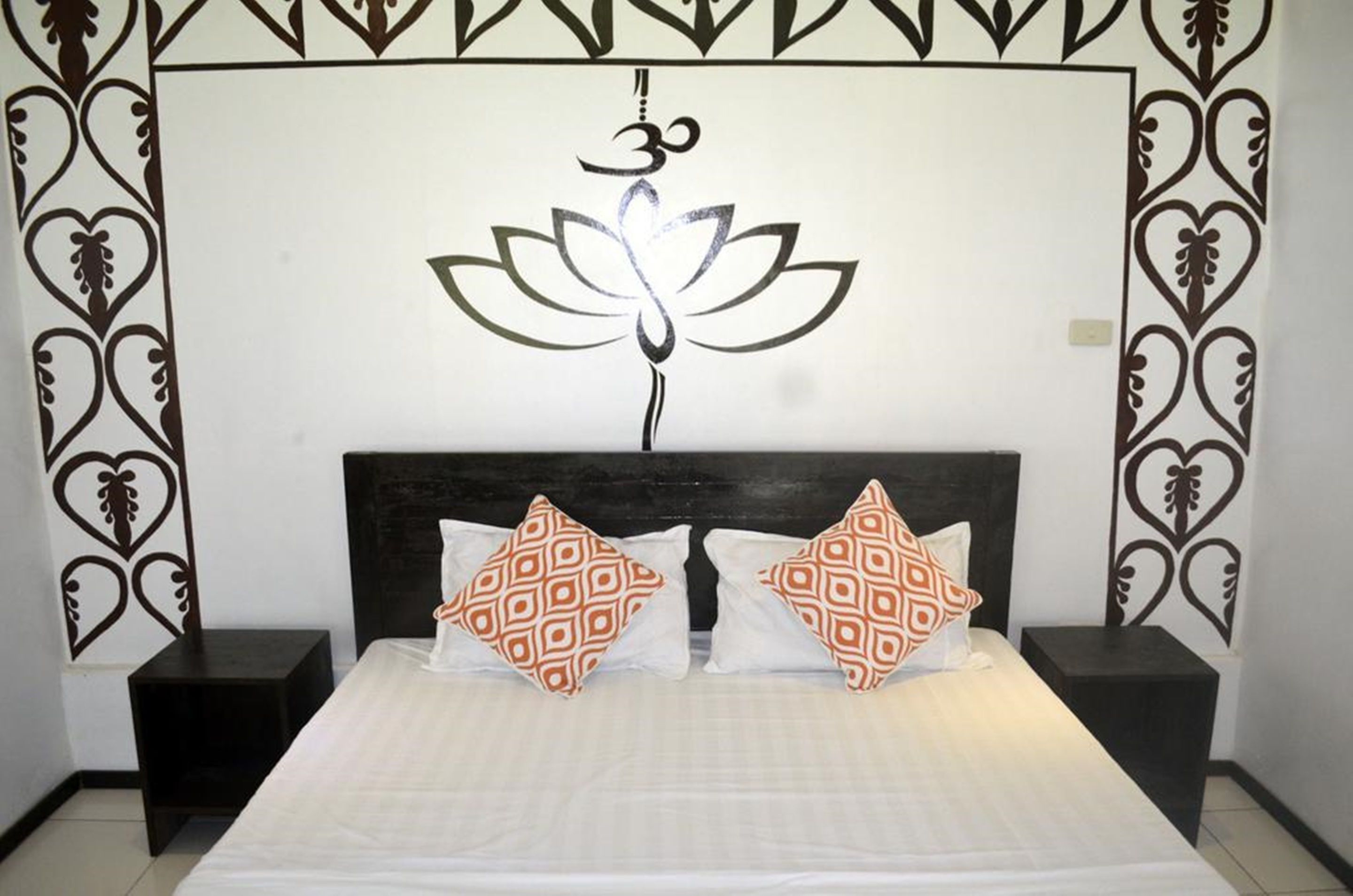 A bedroom with a bed, two nightstands, and a wall with a decorative pattern and a symbol.