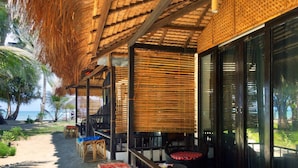 A beachside lounge with thatched roof, wicker furniture, and a view of the ocean. - Peace & Love Beach Club (Roxas)