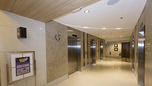 Moderni hotellikäytävä, jossa on kiillotettu lattia, kyltti kuntosalille ja useita hissejä.