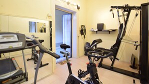 A home gym with a treadmill, stationary bike, and elliptical machine. - B&B Isola Memmia (Padova)