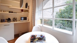 A modern kitchen with white cabinetry, a microwave, and a coffee maker on the counter. There is a window with a view of greenery outside. - B&B Isola Memmia (Padova)