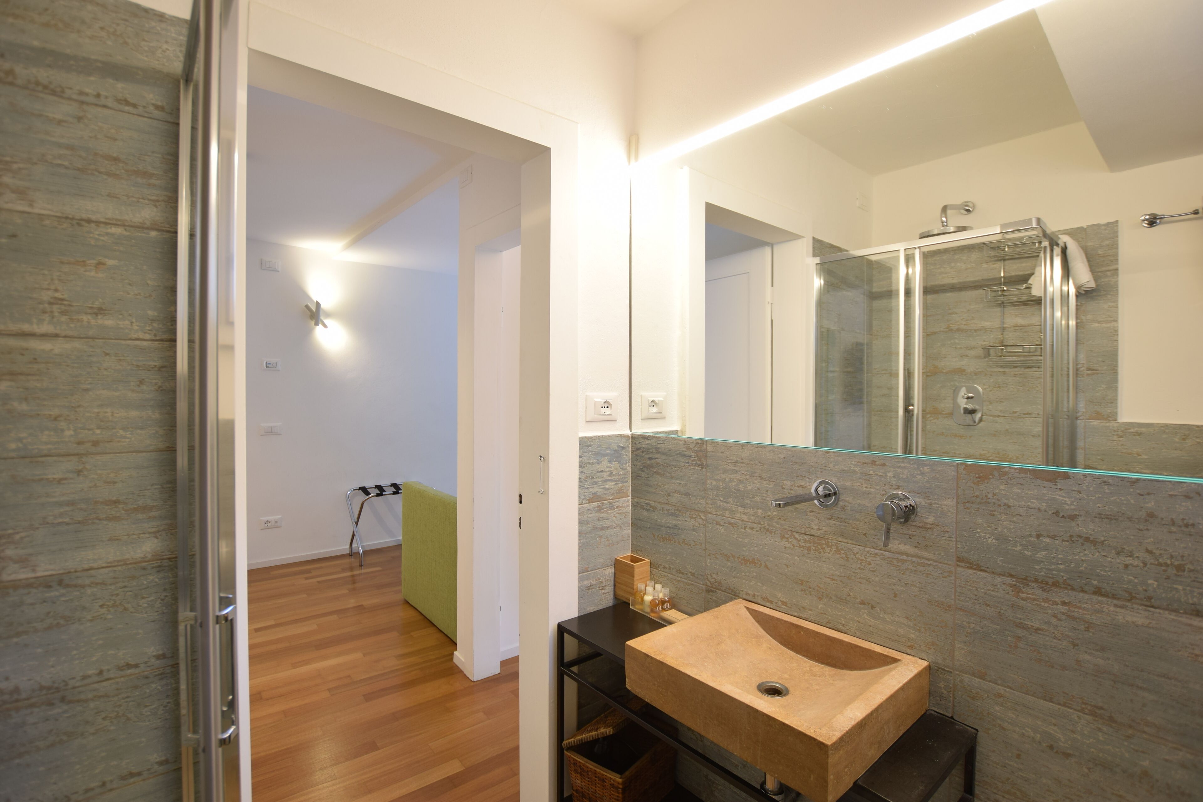 Ein modernes Badezimmer mit einem Holzkosmetikschrank, einer Duschkabine aus Glas und einem sichtbaren Handtuchhalter.