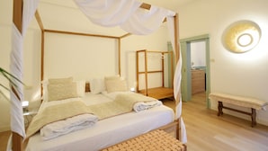 A four-poster bed with a canopy, a wooden bench, and a round mirror on the wall. - B&B Isola Memmia (Padova)