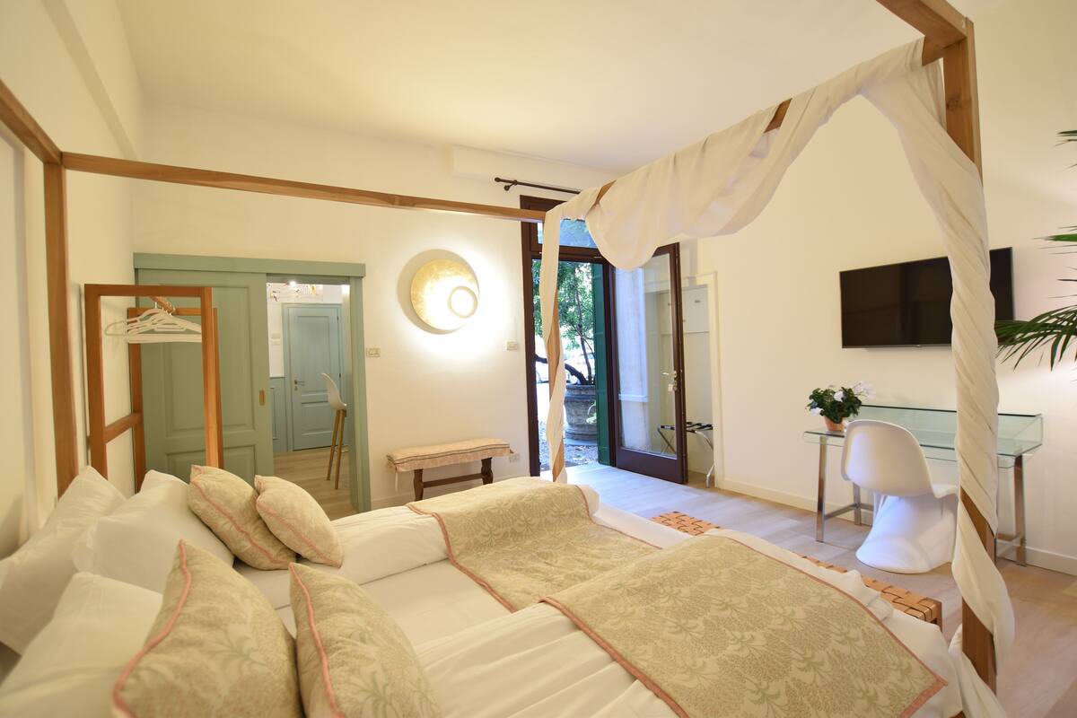 A bedroom with a canopy bed, a desk, and a chair.