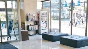 A modern lobby with a glass entrance, seating area, vending machine, and a clean, reflective floor. - Hotel Ascent Plaza Hamamatsu (Hamamatsu)