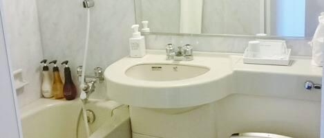 A bathroom with a sink, mirror, toilet, and bathtub.