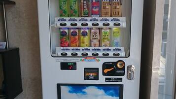 A vending machine with various drinks and snacks, including Yakult, coffee, and tea.