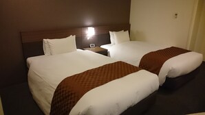 A hotel room with two beds, a nightstand, and a wall-mounted light. - Hotel Ascent Plaza Hamamatsu (Hamamatsu)