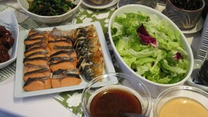 A table with various dishes including salmon, salad, and bowls of sauces. - Hotel South Garden Hamamatsu (Hamamatsu)