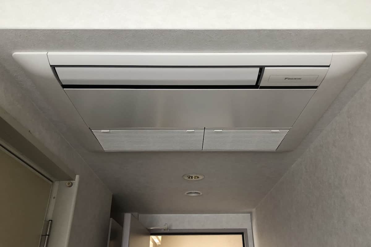 Un climatizzatore a soffitto con pannello di controllo e bocchetta di areazione.