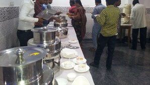 A buffet setup with multiple serving stations and people serving themselves.