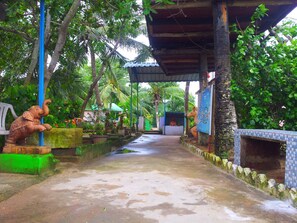 A covered pathway with a statue of an elephant, surrounded by lush greenery and a tiled wall. - Daaven's Island Resort (Krushnaprasad)