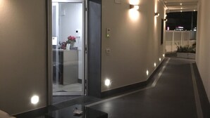 A modern hallway with recessed lighting, a glass door leading to a room, and a small table with a vase. - 8 Room Hotel (Catania)