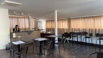A modern restaurant with a bar area, multiple seating options including tables and chairs, and a clean, contemporary interior design.