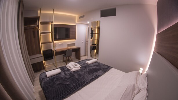 A modern hotel room with a large bed, a desk, and a walk-in closet. - 8 Room Hotel (Catania)