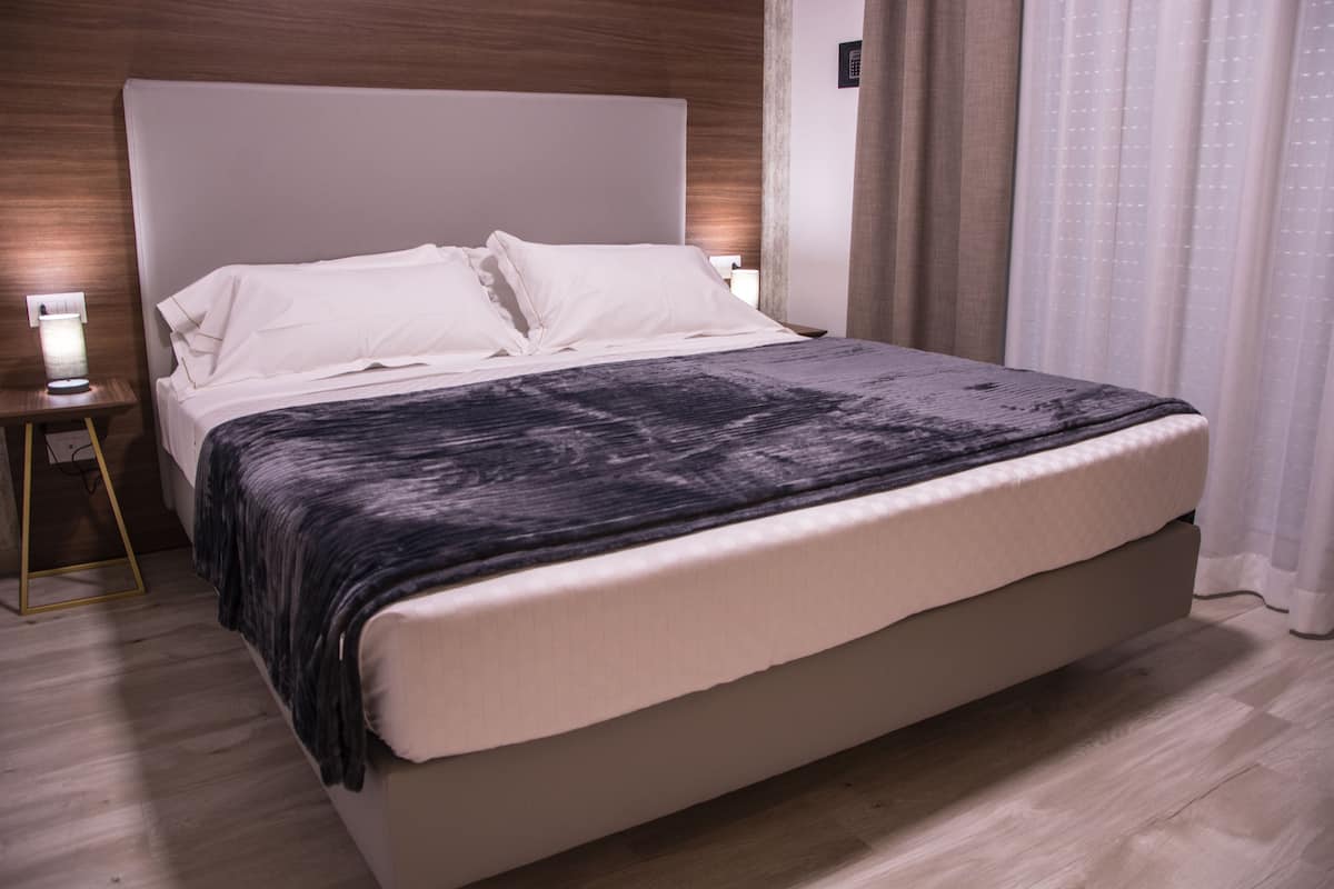 Una habitación de hotel moderna con una cama grande, una mesita de noche y un pequeño tocador.