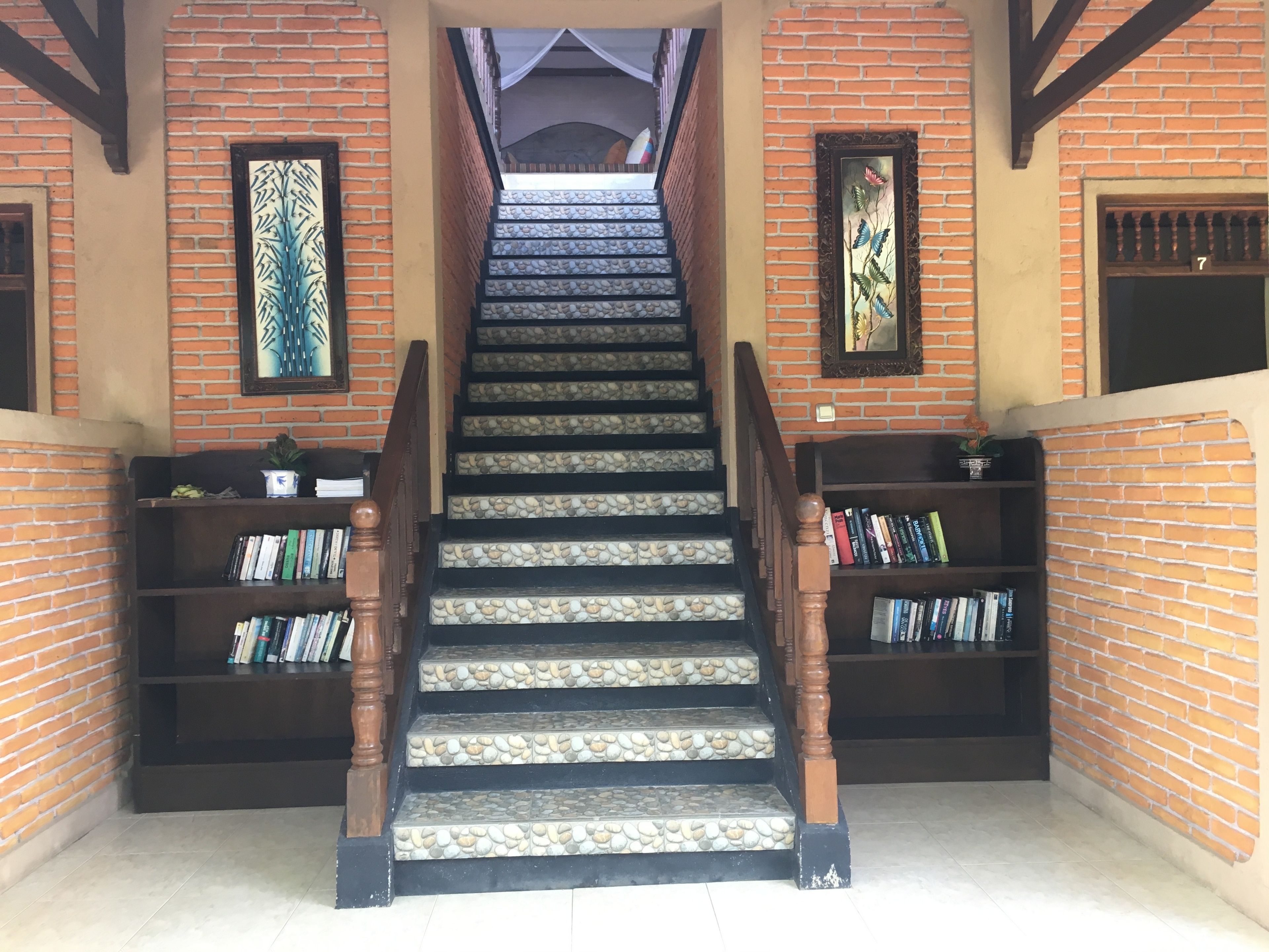 Eine Treppe mit Steinstufen und Holzgeländern, gesäumt von Bücherregalen mit Büchern.