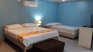 A room with two beds, a desk, and a bench. - Alma's Guesthouse (Panglao)