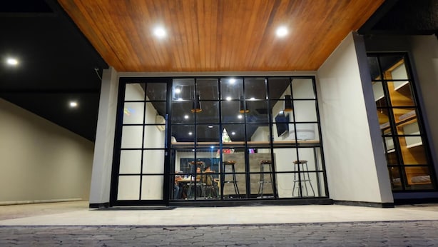 A modern building with a wooden ceiling, large glass windows, and a visible interior with tables and chairs. - Livinn Hostel City Center Surabaya (Surabaya)