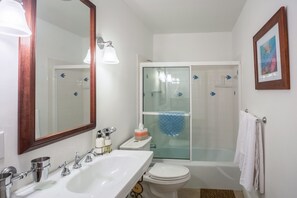 Un baño con lavamanos, inodoro y ducha con mampara de vidrio.