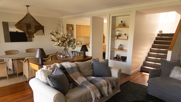 A modern living room with a sofa, a coffee table, and a dining area with a table and chairs.