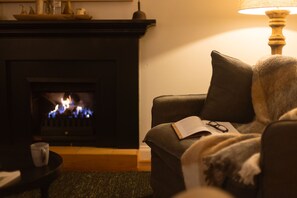 Ett vardagsrum med en öppen spis, en soffa, en lampa och en bok.