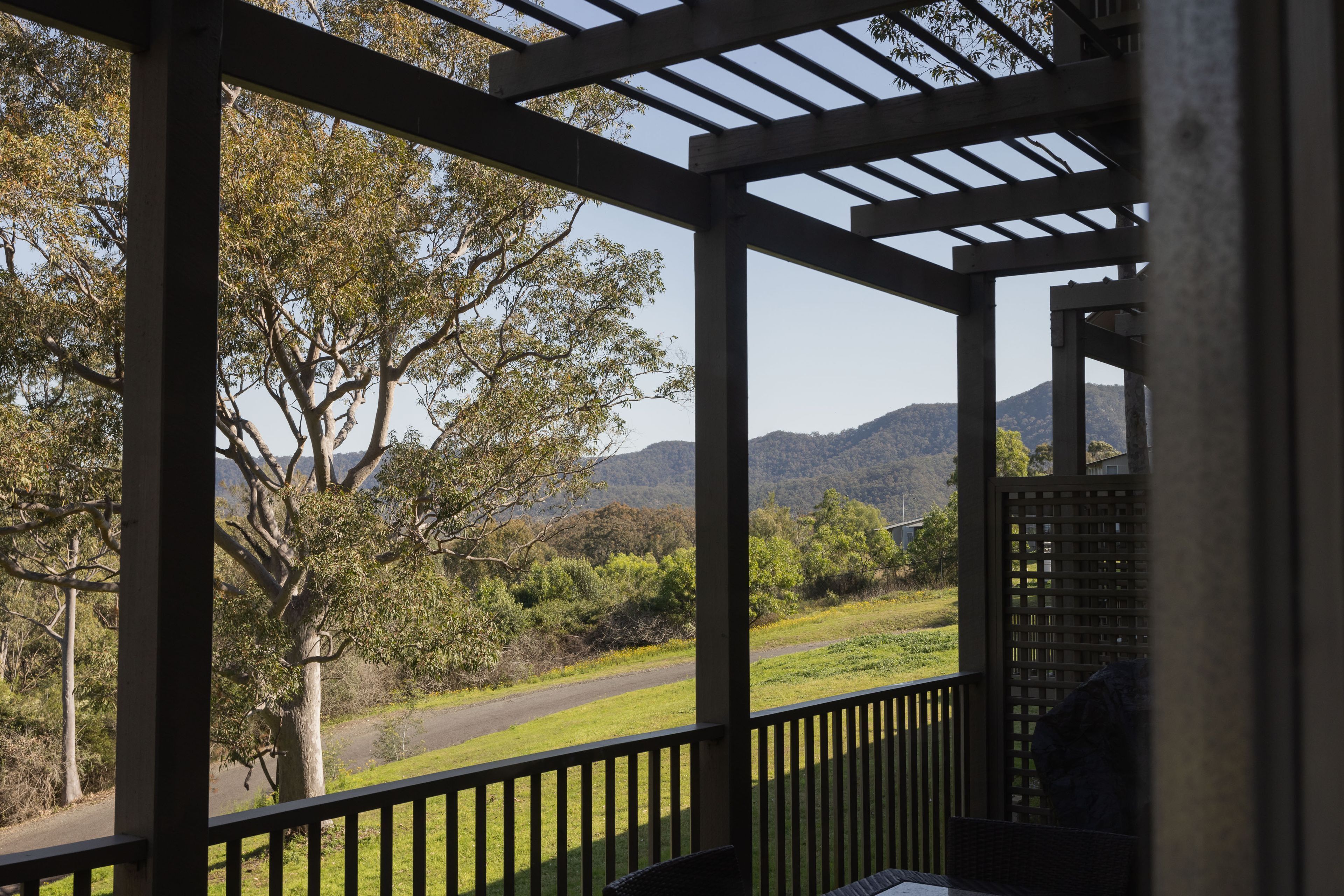 A covered outdoor area with a view of a road and trees.