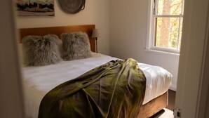 A bed with a wooden headboard, two fluffy pillows, a green blanket, and a painting on the wall. - Tempranillo 3br Villa within Cypress Lakes Resort (Pokolbin)