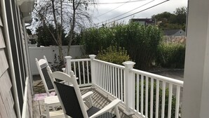Une terrasse en bois avec des rampes blanches et deux fauteuils à bascule.