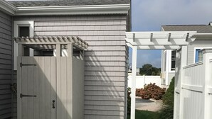 Un jardin avec un abri de jardin, une pergola et une clôture blanche.