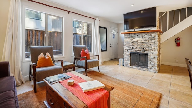 A living room with two armchairs, a coffee table, a fireplace, and a TV mounted above it.