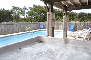 Un jacuzzi con muelle de madera y una piscina al fondo.