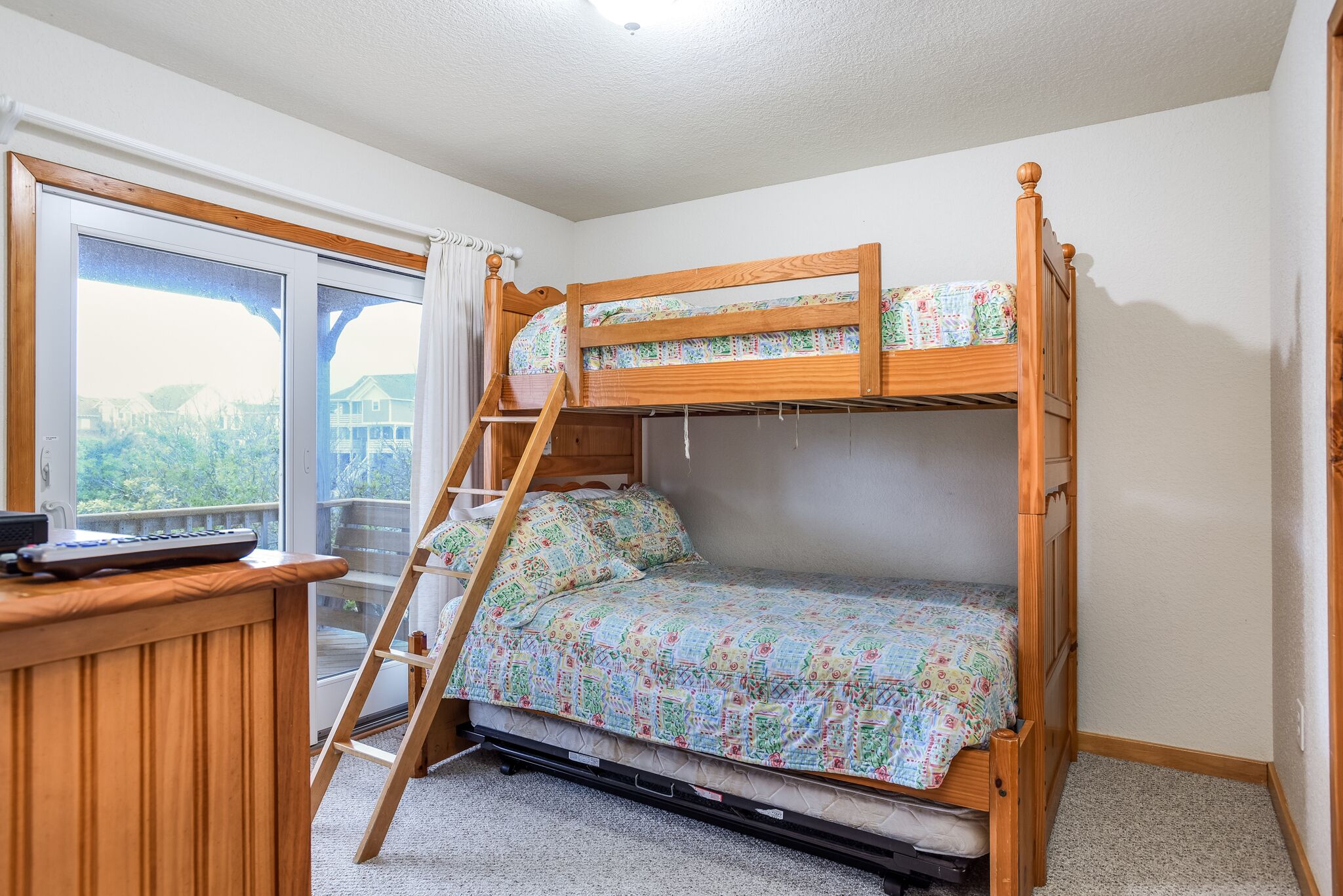 A bunk bed with a wooden ladder, a desk with a keyboard, and a window with curtains.