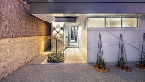 A modern building with a brick wall, a glass entrance, and a small garden with plants. - The Hidden Door Bowral Villa - the Heart of Bowral (Bowral)