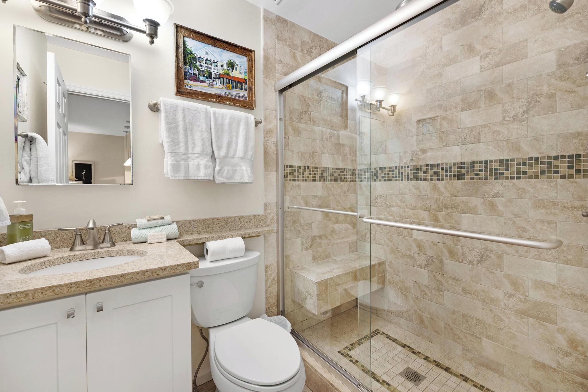 Un baño moderno con ducha de vidrio, lavabo con encimera de mármol y retrete.