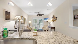 A kitchen with granite countertops, a stainless steel sink, pendant lights, and a ceiling fan. - Another Three Hour Tour at The Truman Annex in Key West (Key West)